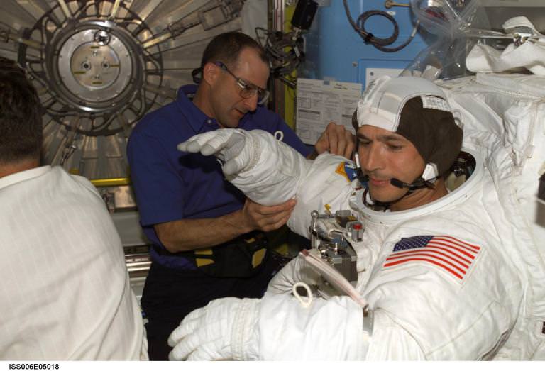 (زندگی در مریخ - مهندس پرواز پِتی، به فضانورد هرینگتون کمک میکند تا لباس برون ناوی خود را بپوشد، منبع: ناسا)